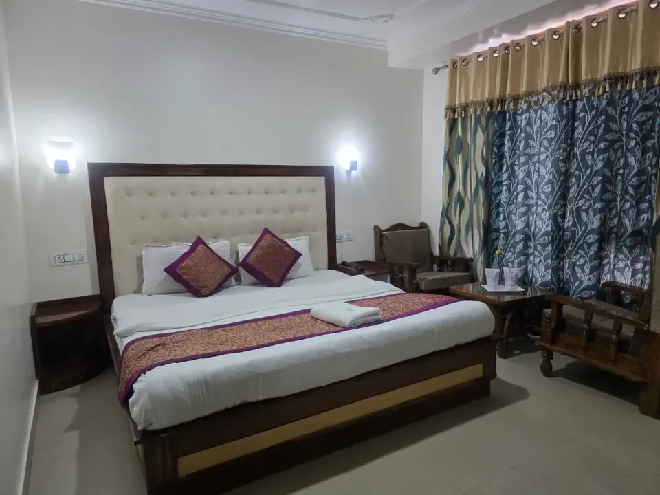 Standard room with a cream tufted headboard, purple cushions and leaf-print curtains